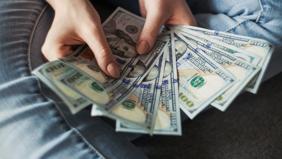 Hands counting a fan of US dollar bills