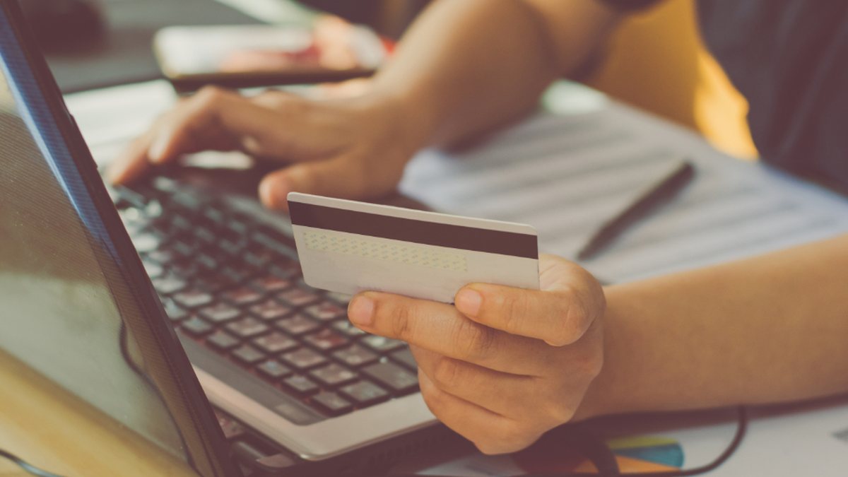 Hands typing on a laptop while holding a credit card