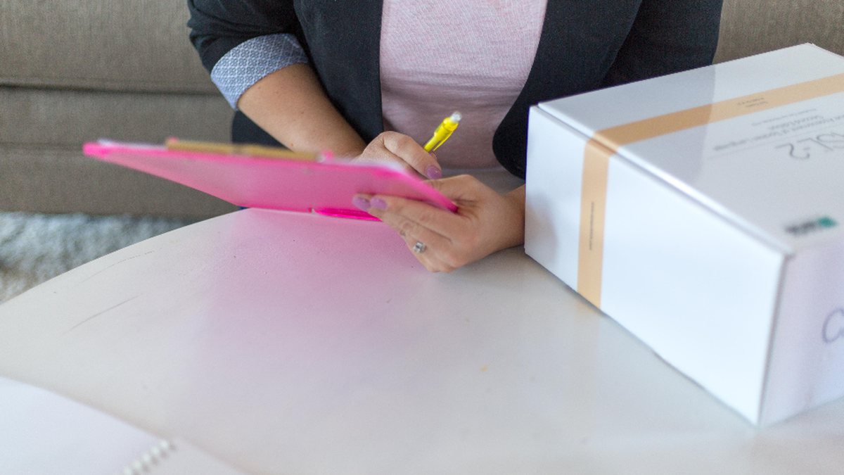 Person checking a clipboard next to a packaged box