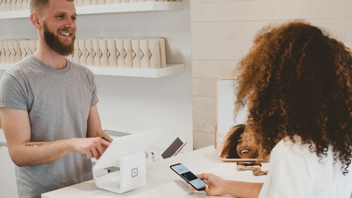 Shop assistant at a checkout taking payment from a customer
